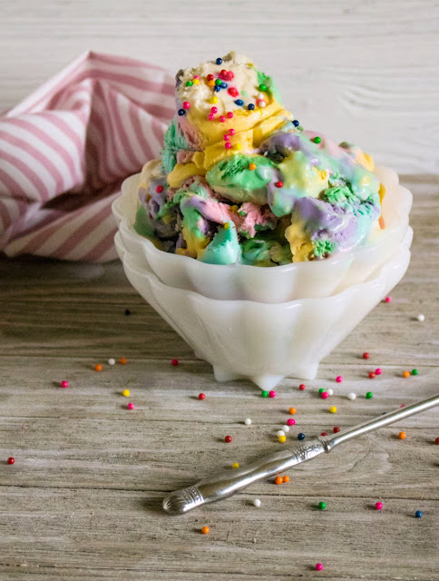 Enjoy the taste of birthday cake in no churn ice cream form! This recipe comes together quickly and can be easily colored to match your party's theme! bowl of colorful ice cream with sprinkles everywhere