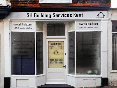 Photograph of shop front with vinyl graphics and lettering. The main windows have text discriving the types of building work they do, with window frosting applied to the back to make the text stand out.