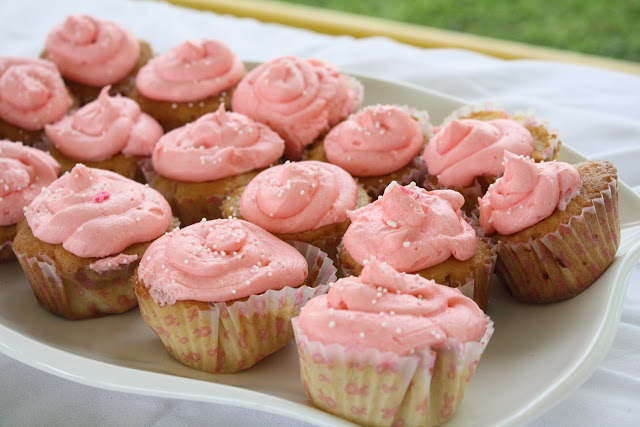 A batch of cupcakes with pink frosting, on a white tray.