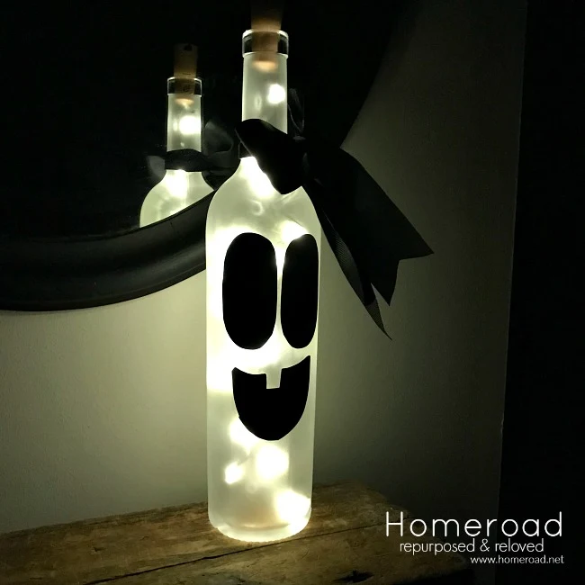 Ghost lighted wine bottle with face and bow