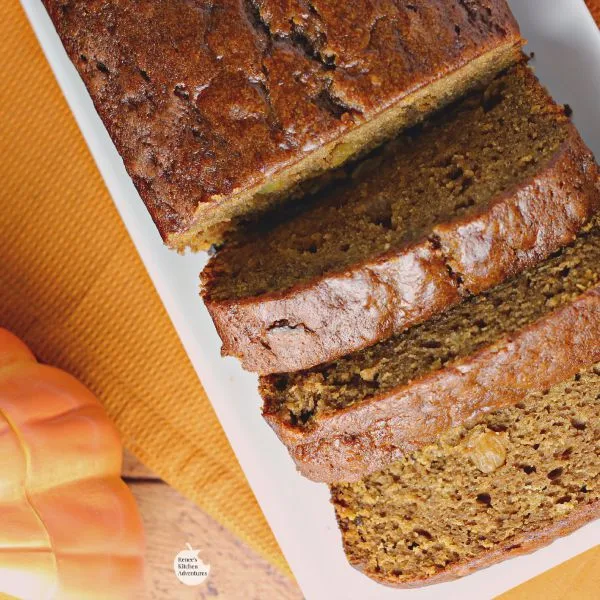 Spiced Pumpkin Bread by Renee's Kitchen Adventures overhead shot of bread on a white tray with slices and a pumpkin off to the right side