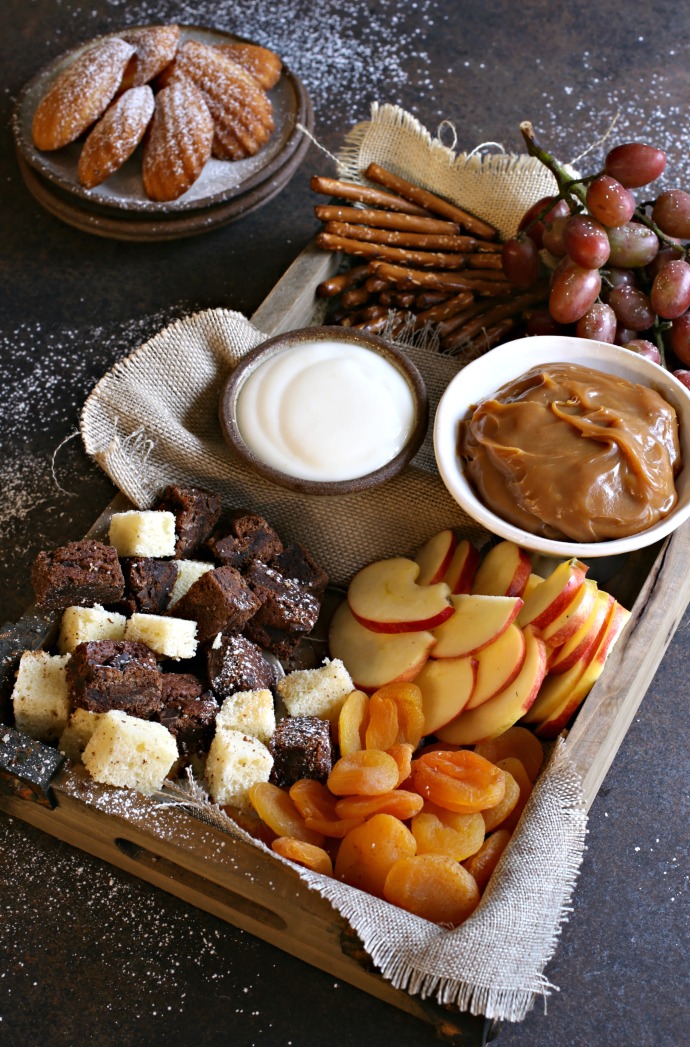 Recipe for creating a dessert treat board with cubes of cake, cookies, fresh fruit, dried fruit and sweet caramel and yogurt dips.