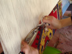 A young lady working on a rug.