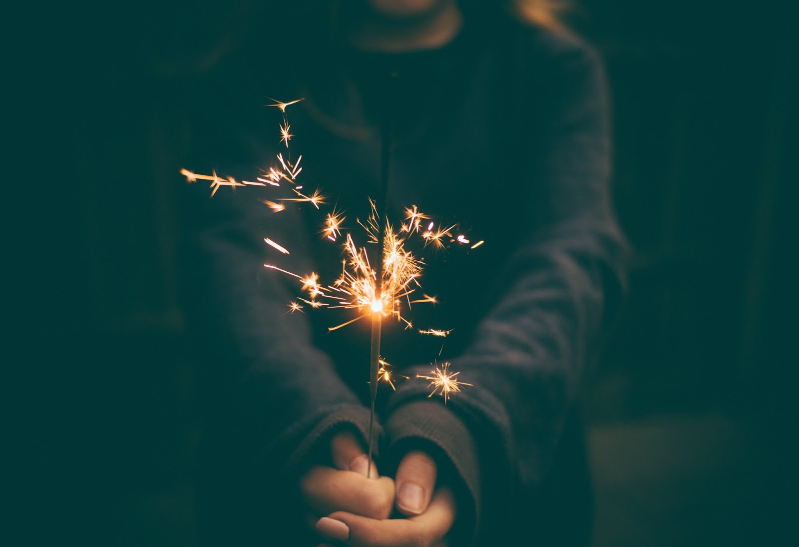 Hands holding a sparkler firework in the dark