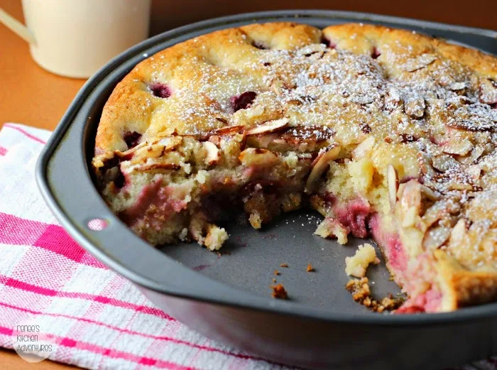 Cherry Delicious Almond Cake in the pan with a slice missing