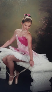 the young dancer in pointe attire sitting on a bench tying her pointe shoe