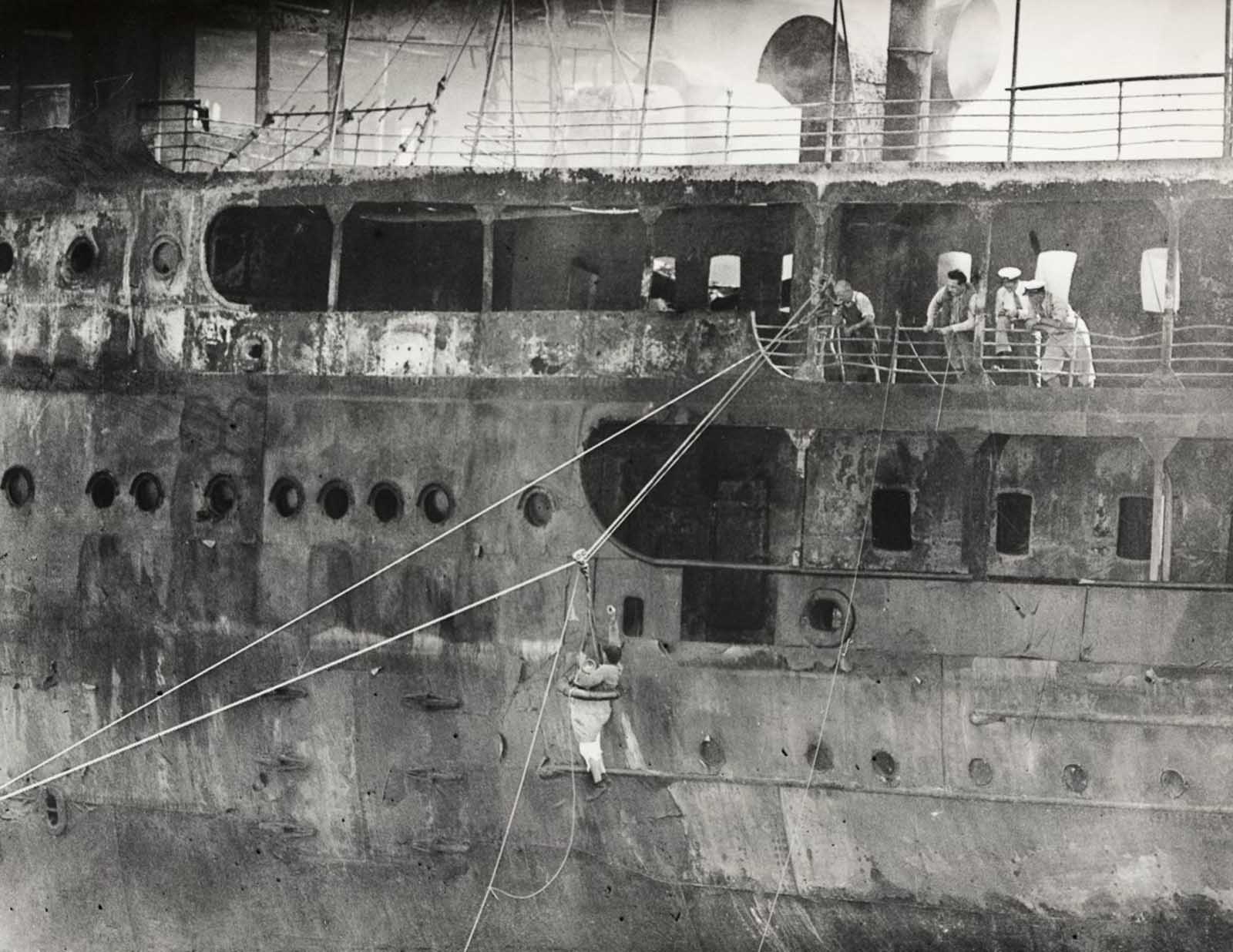Men climb aboard the wreck to search for bodies.