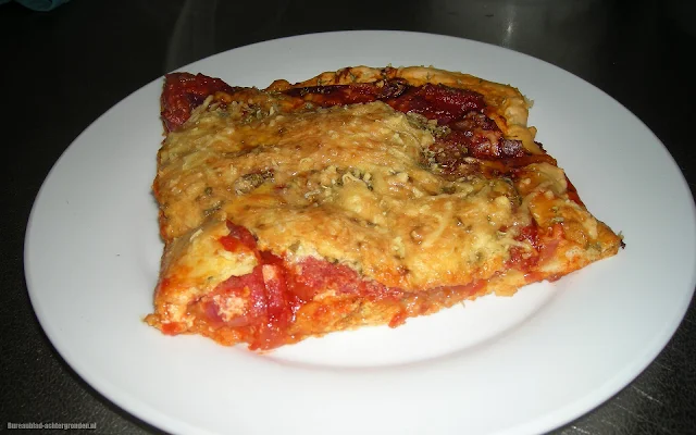 Foto van een stuk zelfgemaakte pizza op een wit bord