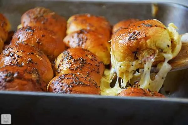Oven Baked Ham and Cheese Sliders being served from casserole dish
