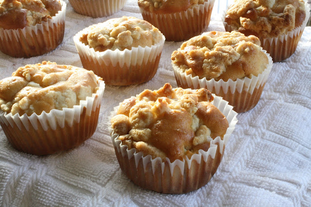 Three rows of apple streusel muffins on a tablecloth.