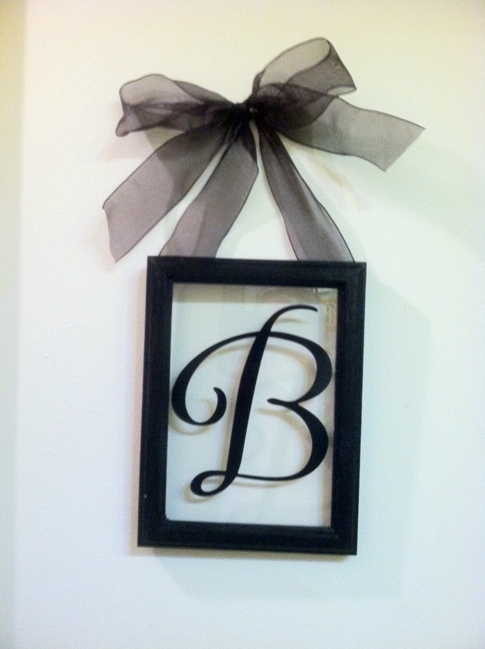 a wee Meenit Monogram Vinyl letter behind glass frame