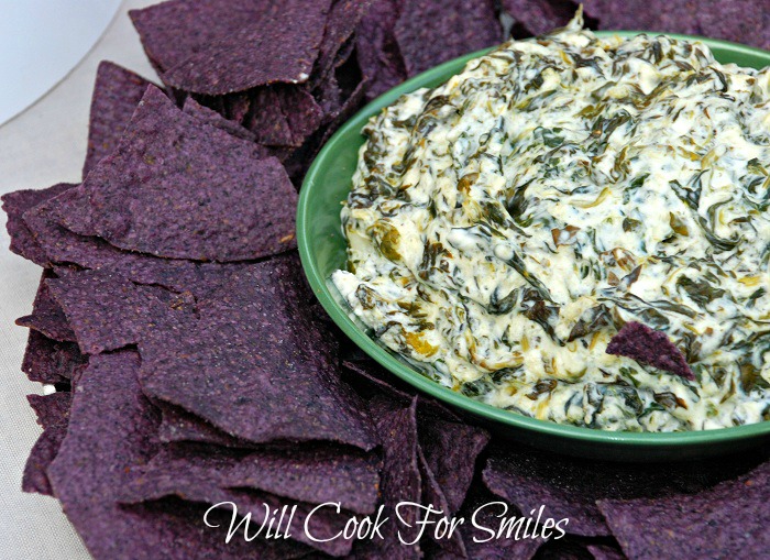 Spinach Parmesan Dip in a green bowl with purple tortilla chips