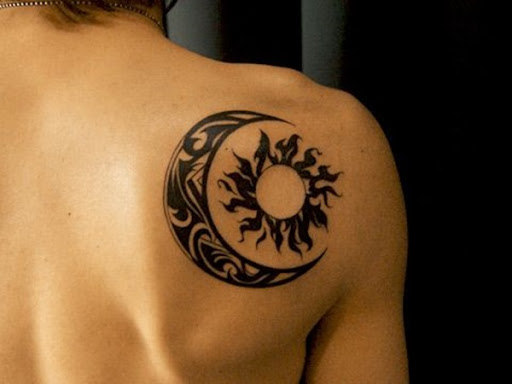 Esta inspiração tribal tatuagem, retratado em tinta preta, mostra uma lua crescente, envolvendo em torno de um sol sobre o utente direito ombro.
