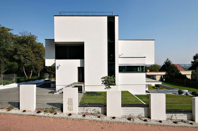 White Wall Made from Concrete and Vast Green Garden Filled with Green Grass and Little Plants