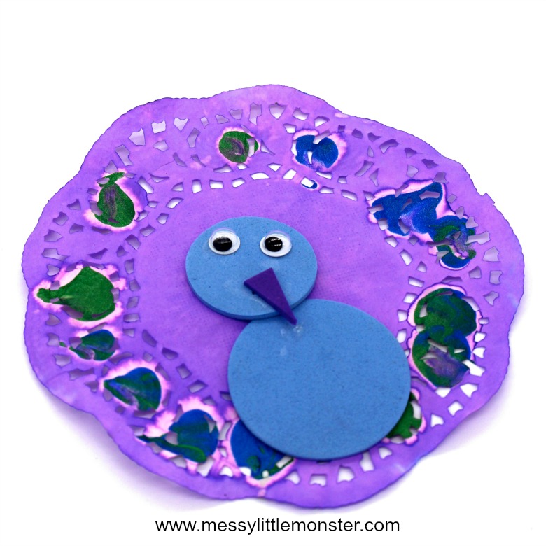 Paper doily peacock craft for kids with fingerprints. Easy enough for toddlers and preschoolers, this activity makes a great addition to a bird themed project.