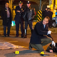 Jonny Lee Miller as Sherlock Holmes examining corpse body at a crime scene in CBS Elementary Season 3 Episode 8 End of Watch Elementary Sherlock Holmes examining corpse body at a crime scene in CBS Elementary Season 3 Episode 8 End of Watch