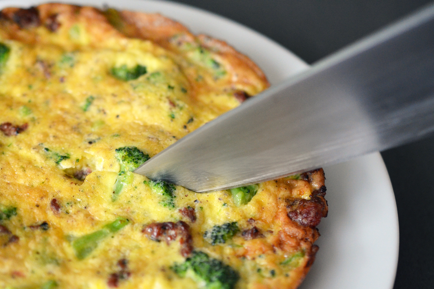 Close up of a knife slicing a piece of Easy Paleo Frittata.