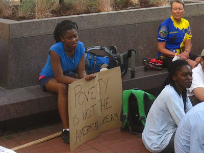 Young woman with sign reading Poverty is not the American dream