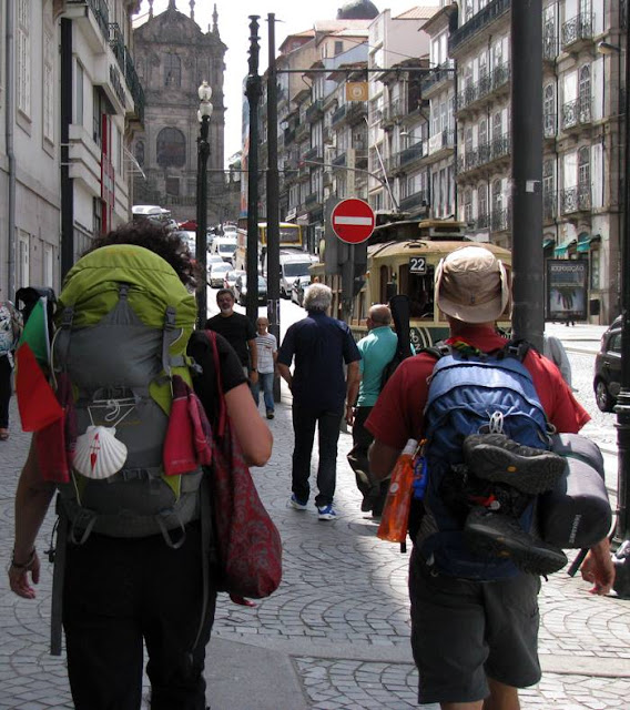 Dois peregrinos de Santiago de Compostela pelas ruas do Porto, com um eléctrico e igreja dos Clérigos ao fundo