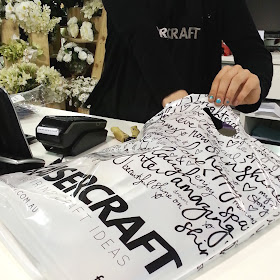 Shop assistant at Kaisercraft packing items into a shopping bag.