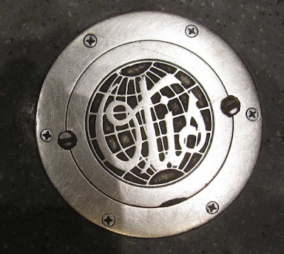 Worn steel Otis logo, globe shape, script letters