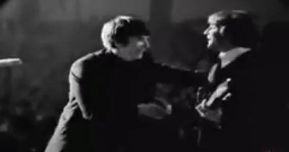 John Lennon, de The Beatles, en concierto 1964. Hombre sube a saludar a John.