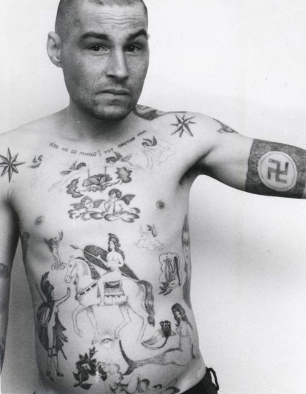 Text across the chest reads ‘He who is not with me is against me.' The swastika and Nazi symbols may mean the owner has fascist sympathies, though they are more usually made as a protest and display of aggression toward the prison or camp administration. During the Soviet period the authorities often removed these tattoos by force either surgically or by using an etching method. A tattoo of a mermaid can indicate a sentence for rape of a minor, or child molestation. In prison jargon the nickname for a person who commits this type of crime is 'amurik,' meaning ‘cupid’, ‘shaggy,' or a universal ‘all rounder.' They are ‘lowered’ in status by being forcibly sodomised by other prisoners, sometimes in groups.