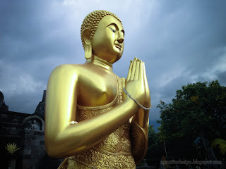 Side Bottom View Golden Standing Buddha Statue In The Buddhist Temple And Cloudy Sky In Bali Indonesia