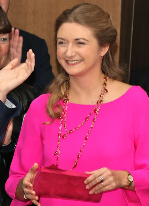 Princess Stephanie wore a fuchsia color Prada Dress, Prada Bordeaux Coloured suede shoes, Prada Bordeaux Coloured clutch bag and Colored stone ruby necklace and ruby ring