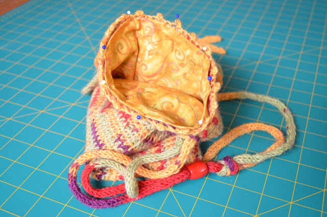 Similar to the previous photo, the bag is resting open to show the lining hem pinned to the bag's opening border.