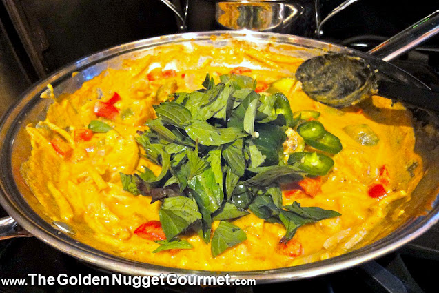 Thai red curry chicken topped with Thai basil in a wok