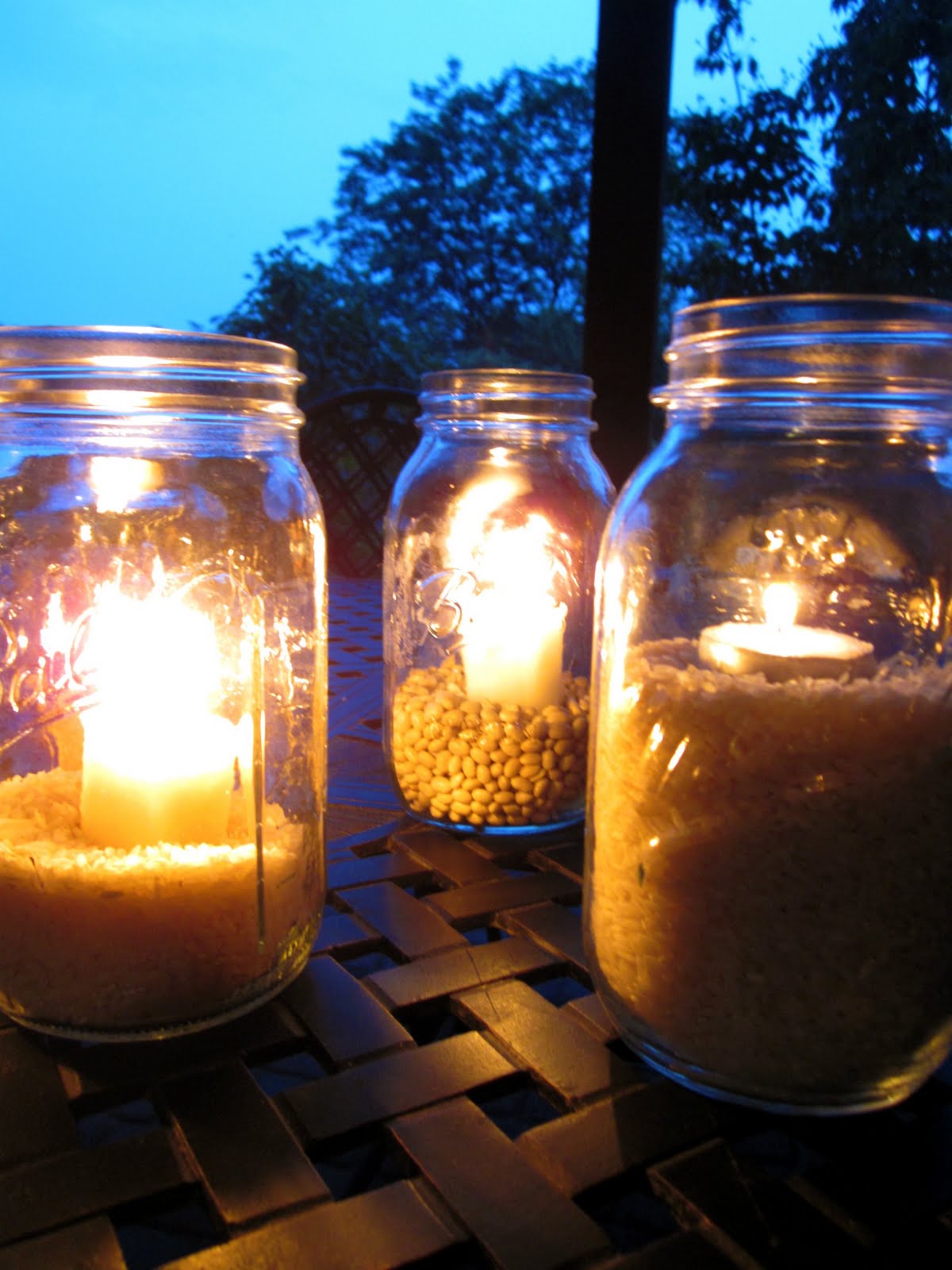 Light up your summer night with beach jar candle holders. A mismatched  group of mason jars sits atop a table. F…
