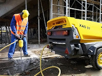 Havalı kırıcı ile bir kaldırım betonunu kıran işçi
