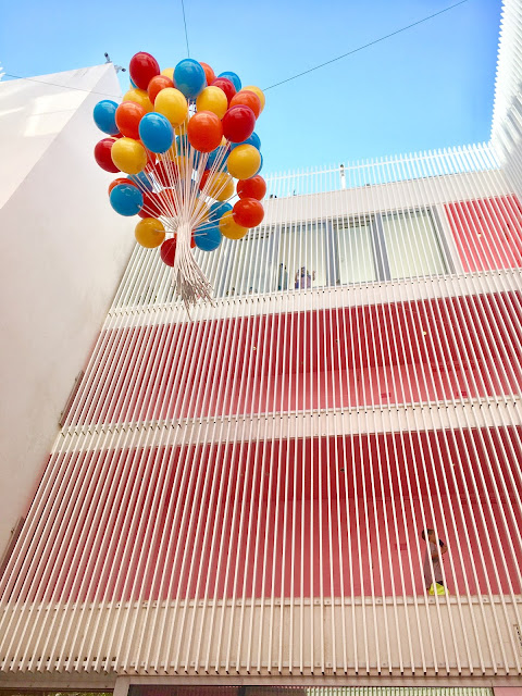 A mass of multicolored balloons float several stories above the photographer