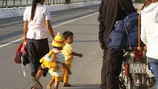 A small Vietnamese child looks at tourists on motorcycles near the border of Laos in Vietnam.