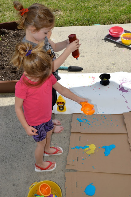 Squirt! Drip! Pour! Process Art Painting For Kids.  Head outside for some messy painting fun for spring our summer.  Preschoolers, kindergartners, and elementary students will LOVE this opportunity to make giant process art.