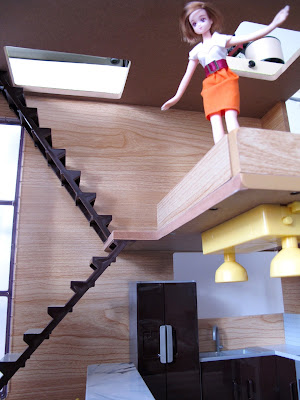 A doll looking over the mezanine railing of the modern Lori Loft to Love dolls' house.
