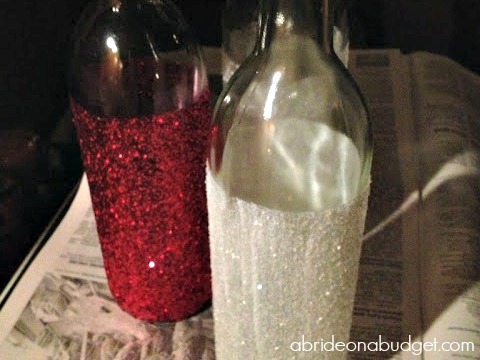 Need a wedding centerpiece or engagement party centerpiece idea? Check out these Glittered Wine Bottle Centerpieces on www.abrideonabudget.com. #glitter #winebottlecraft #winebottlecenterpiece #diyglitteredwinebottle
