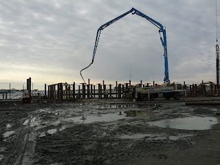 Crane and drill installing pilings at the water's edge.