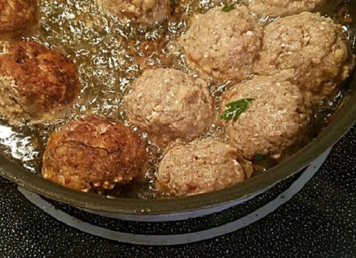 this is ground beef with herbs and spices added to make a round ball then fried in oil in a pan these are cooking in a heavy fry pan and the meatballs will be crispy on the outside and soft inside nicely browned using vegetable or canola oi