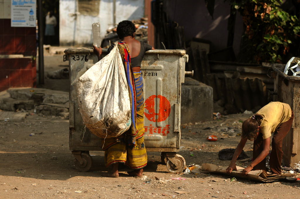 Poverty photo of a woman and a girl digging at a trash can in Mumbai, India.