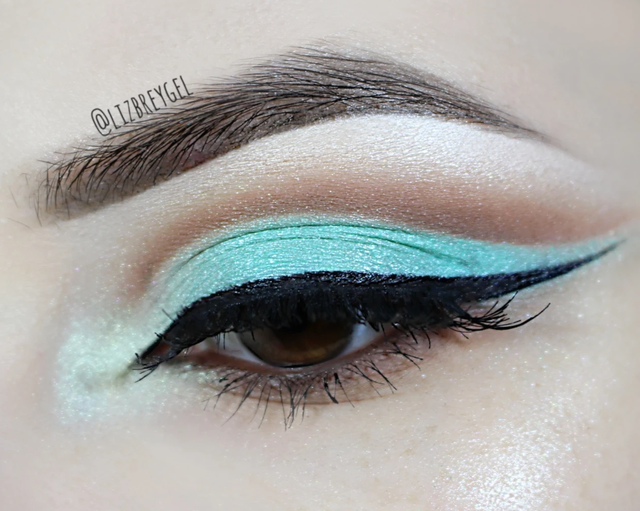 a close-up of a brown eye with a chocolate mint cut crease makeup look inspired by Nicki Minaj
