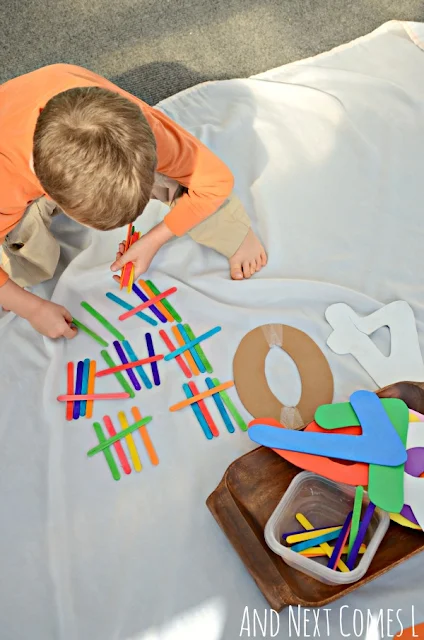 A child doing a math tally marks activity using colored craft sticks