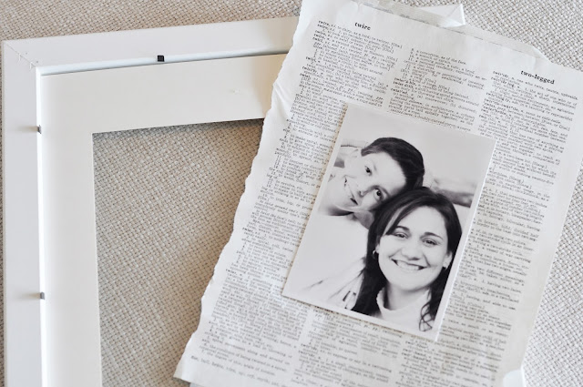 Create a vintage dictionary photo gallery wall with an old dictionary, black and white photos, and white frames from www.jengallacher.com. Includes tutorial photos. #gallerywall #photogrid #vintagedictionarypaper