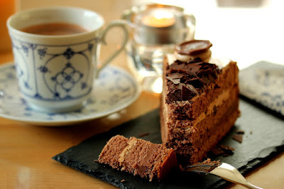 Kawałek czekoladowego ciasta na stole obok filiżanki kawy