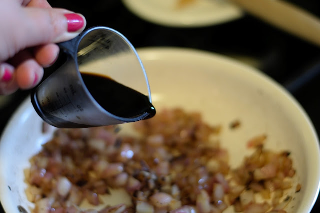 Balsamic vinegar being added to the onions in the pan. 