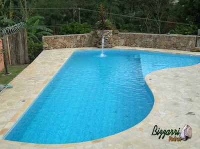Construção de piscina de alvenaria com o muro de pedra, o piso de pedra com caco São Tomé, a cascata de pedra com a bica d'água e os dormentes de madeira.