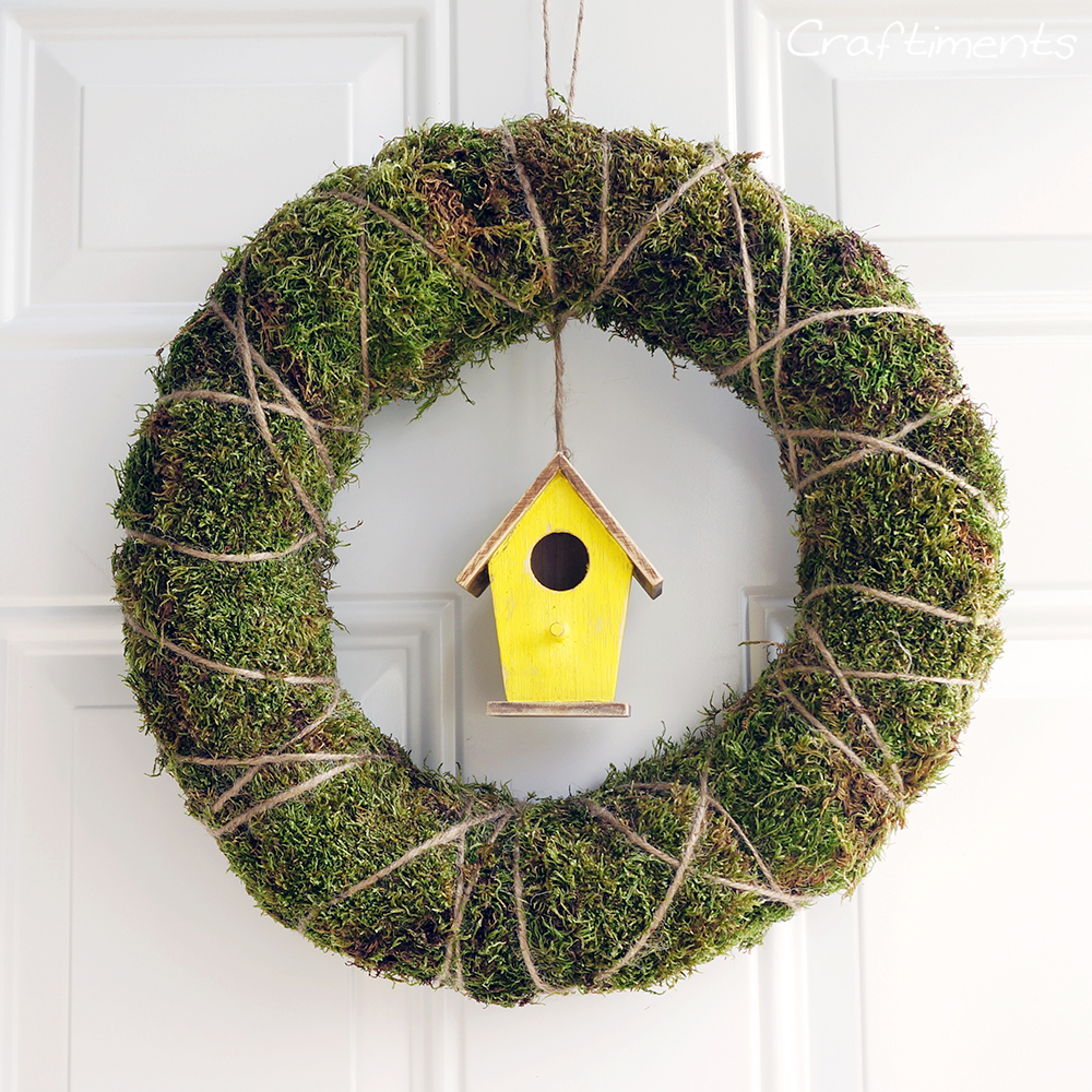 Frugal and easy to assemble moss and twine wreath with birdhouse suspended inside.