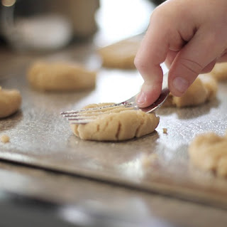 Child using a fork to make patterns on biscuits