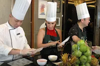 A chef demonstrating a cooking technique to a group of attentive students in a well-equipped kitchen.